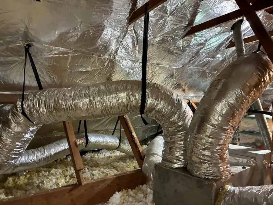 Attic with reflective foil fastened under the roof rafters and insulation on the attic floor